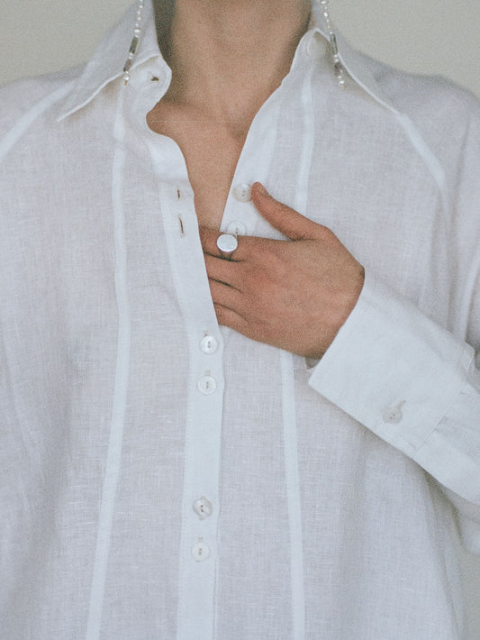 Atelier Magata Ivory white linen shirt with side slit with panel framing front seam and pearl earrings